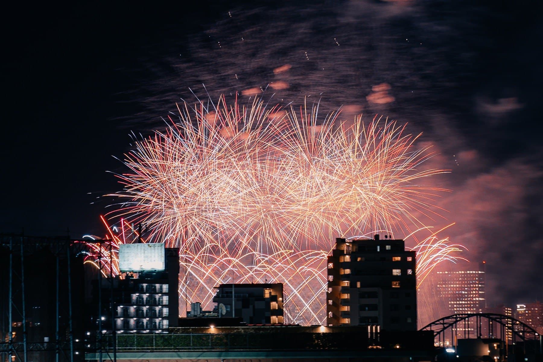 Fireworks filling the sky above a Japanese city riverfront