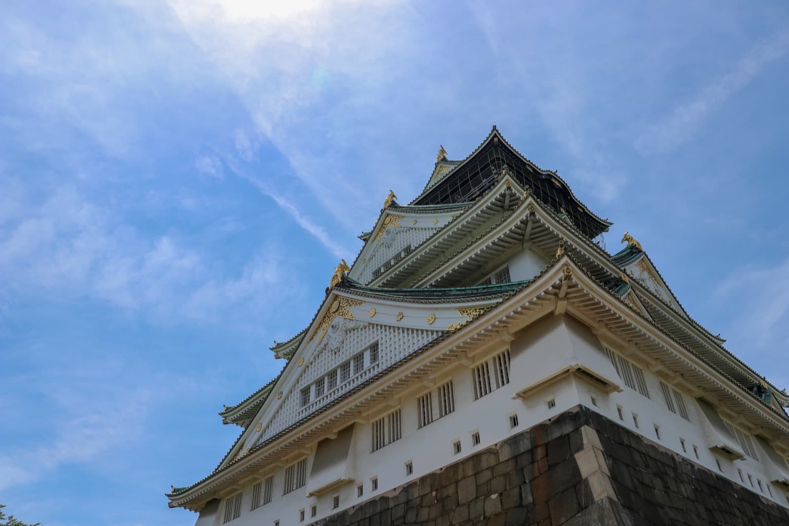 Low-angle view of Osaka Castle under a clear blue sky