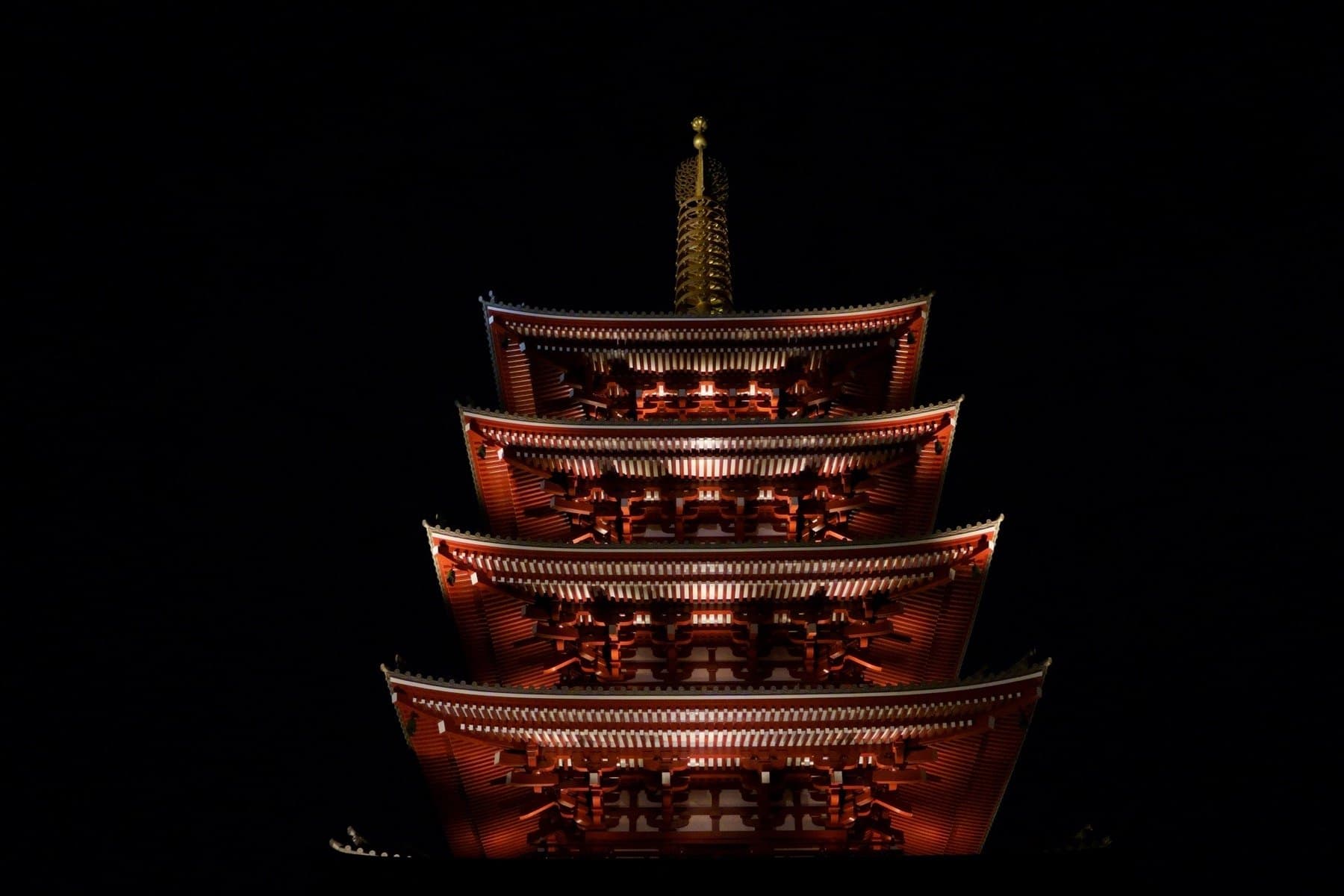 A lit Asakusa temple pagoda against the summer night sky