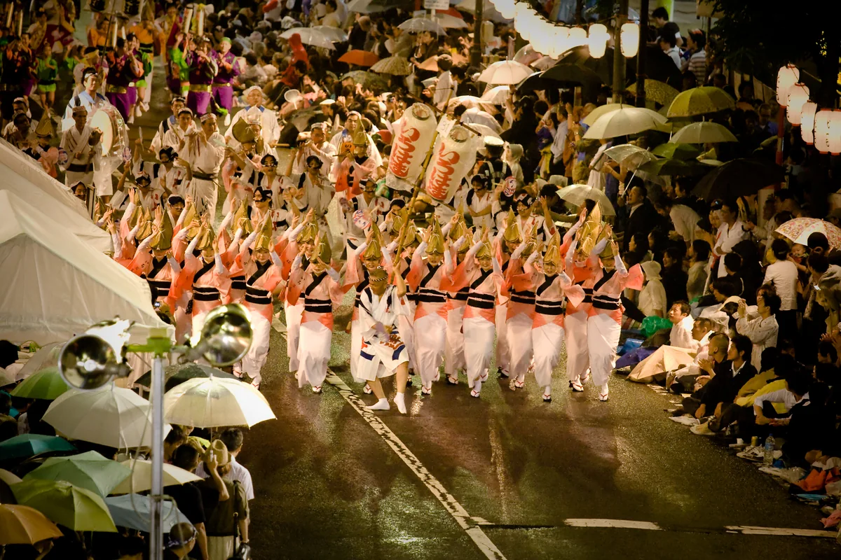Historical Tokyo Koenji Awa Odori dancers and spectators on a rain-lit street.