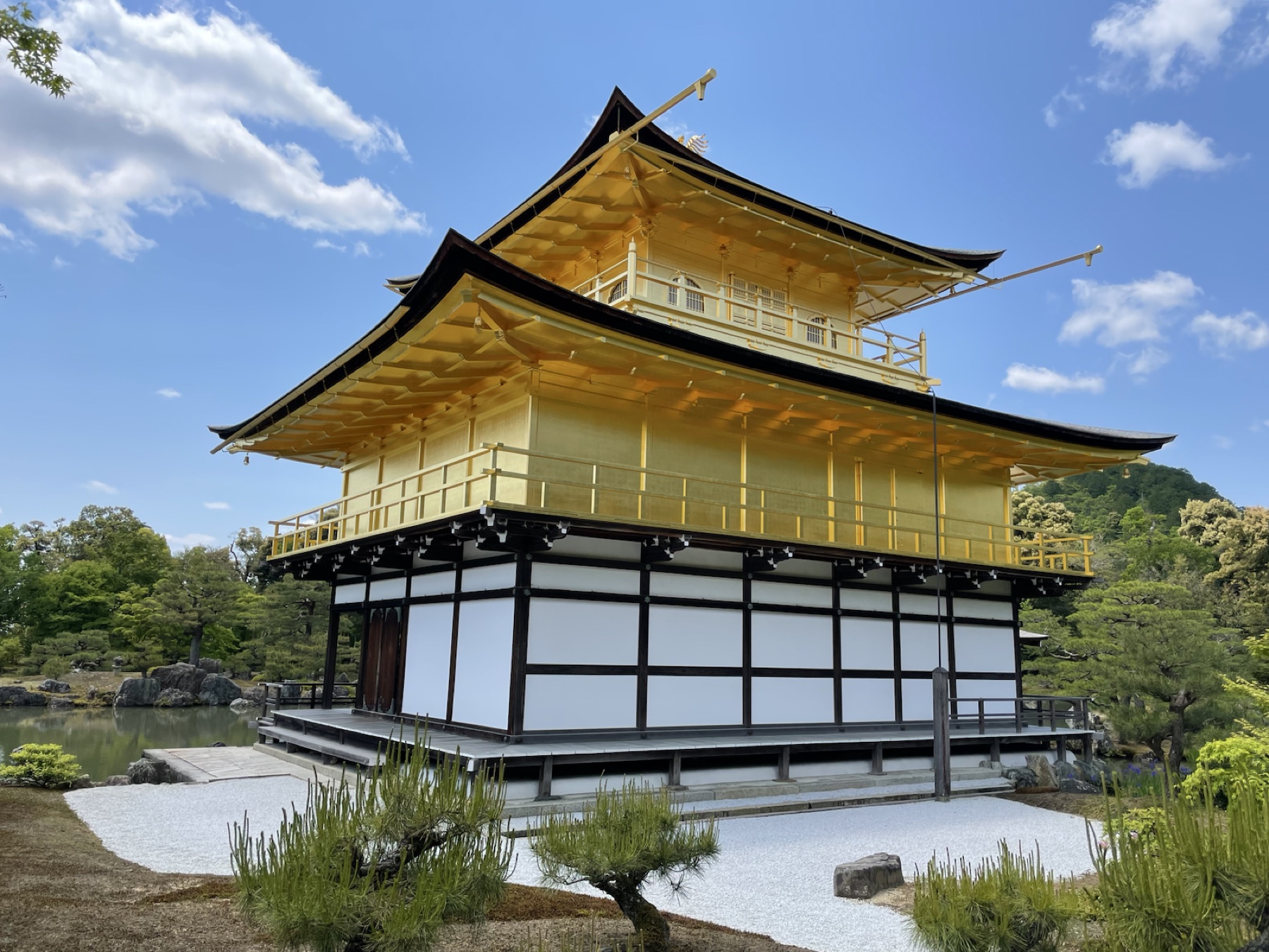 Kinkaku-ji's gold pavilion under a bright blue Kyoto sky.